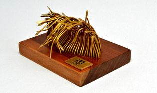 escultura para regalo corporativo hecha en bronce y madera que representa una ola